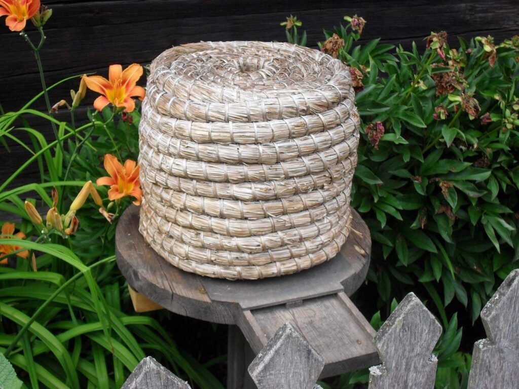 Traditional coiled-straw skep beehive on a wooden stand, the standard medieval hive design
