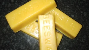 Four molded yellow beeswax bars stamped BEESWAX, the front bar dusted with a pale film