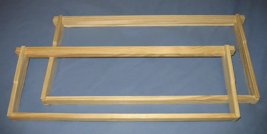 Two empty wooden Langstroth frames on a blue cloth, a 9-1/8-inch deep frame behind a 6-1/4-inch medium