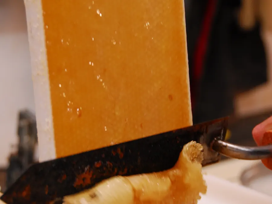 Uncapping knife slicing the wax cappings off a frame of capped honey before extraction