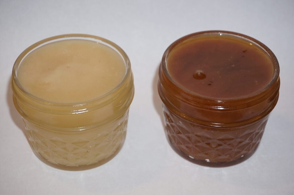 Photo of two jars of creamed honey, one pale and fresh and one darkened after two years of storage