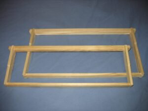 Photo of an empty deep Langstroth frame and a shorter medium frame laid side by side to compare their heights