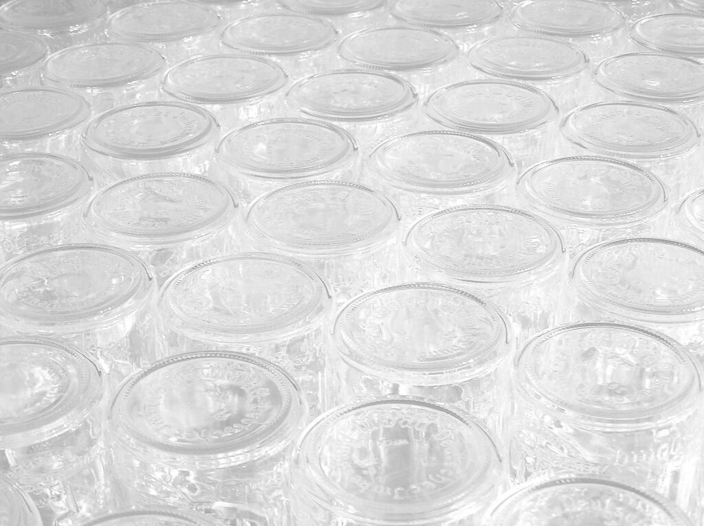 Photo of rows of clean, empty glass honey jars lined up and ready to be filled after the honey harvest