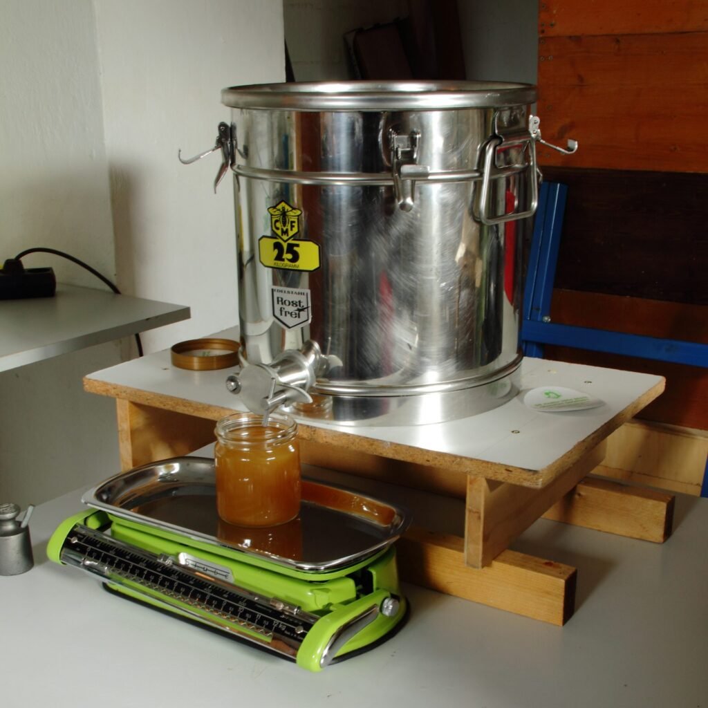 Photo of honey running from the bottom gate of a stainless steel bottling tank into a glass jar set on a kitchen scale