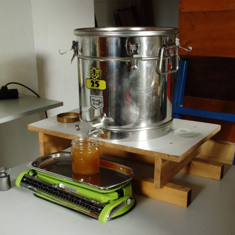 Photo of a stainless steel honey bottling tank with a gate valve filling a glass jar on a kitchen scale
