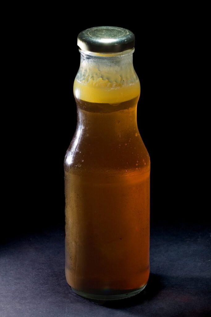Photo of a glass bottle of amber honey with a layer of pale granulated crystals forming at the top