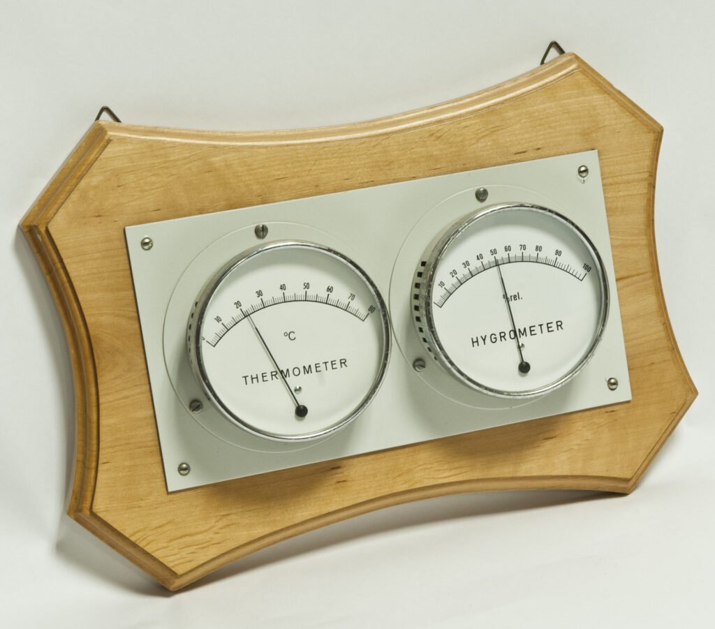 Photo of a wall-mounted dial thermometer and hygrometer pair used to read room temperature and relative humidity