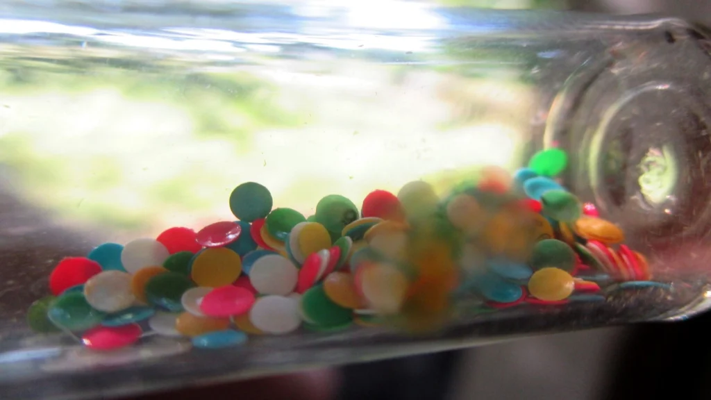 Photo of numbered queen marking discs in white, yellow, red, green and blue inside a clear glass tube