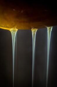 Honey being filtered through mesh screen to remove wax debris after extraction