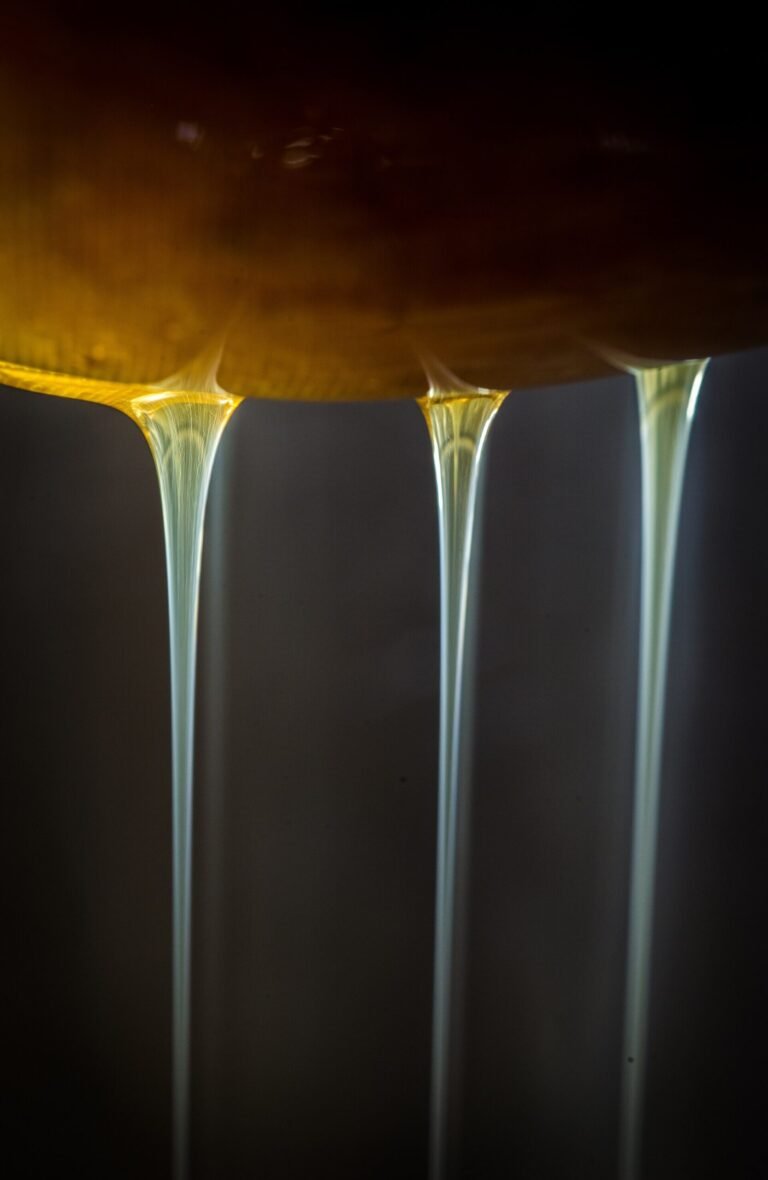 Honey being filtered through mesh screen to remove wax debris after extraction