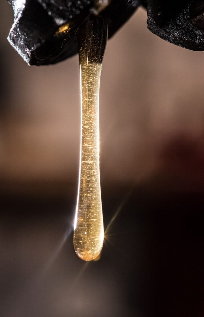 Filtered honey flowing from a settling tank tap Filtered honey flowing from the tap of a settling tank after wax and foam removal