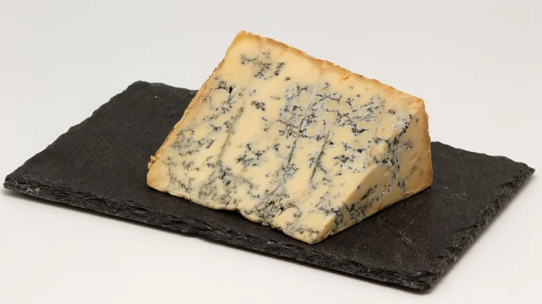 Photo of a wedge of blue Stilton cheese, a classic pairing for bold, dark honey