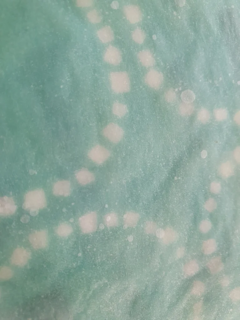 Melted beeswax being spread onto cotton fabric during the DIY food wrap making process