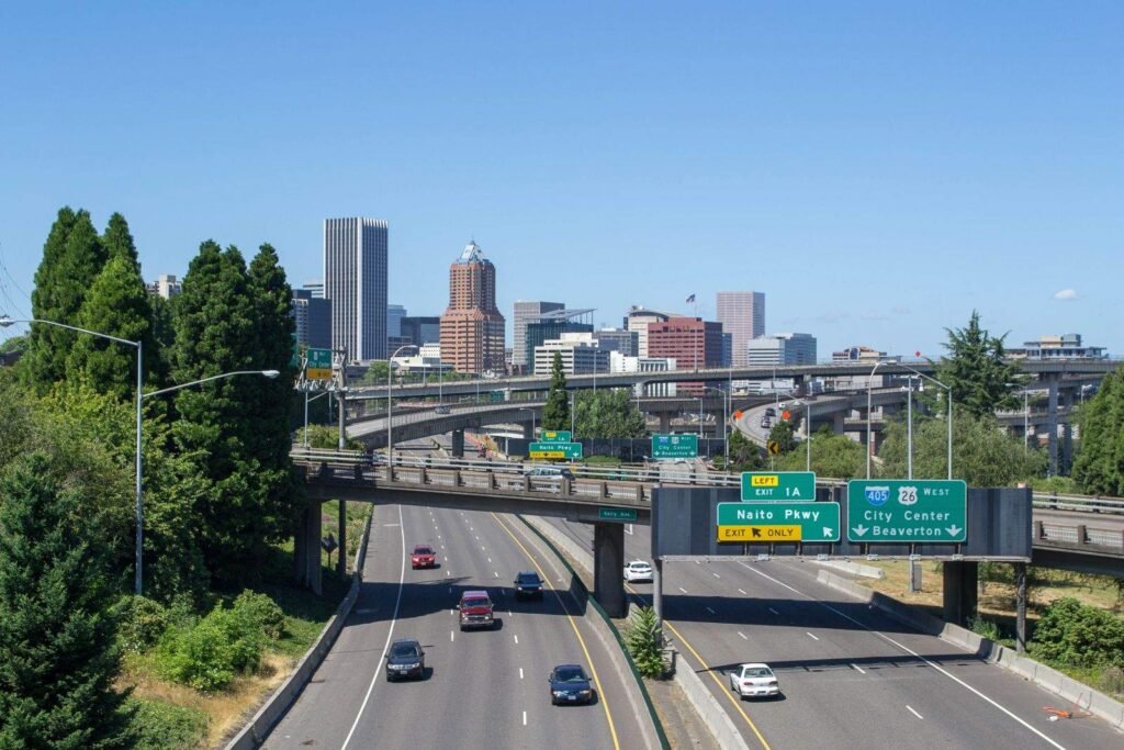 Portland, Oregon downtown skyline viewed from a highway overpass with city center exit signage in the foreground