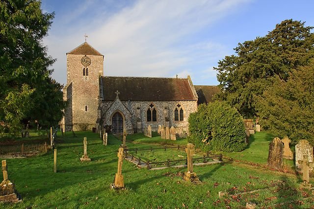 St Lawrence's parish church in Wootton St Lawrence, Hampshire, a flint and stone medieval church with a square tower, seen across its graveyard