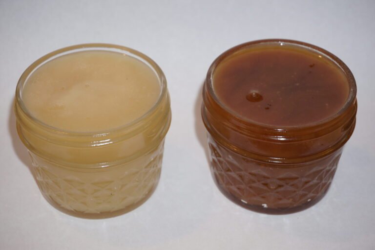 Creamed honey with a smooth spreadable texture in a jar, showing color change from the Maillard reaction after aging