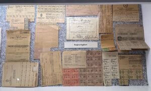 A museum display of worn World War II-era ration cards and stamps for sugar, shoes, textiles, and other goods