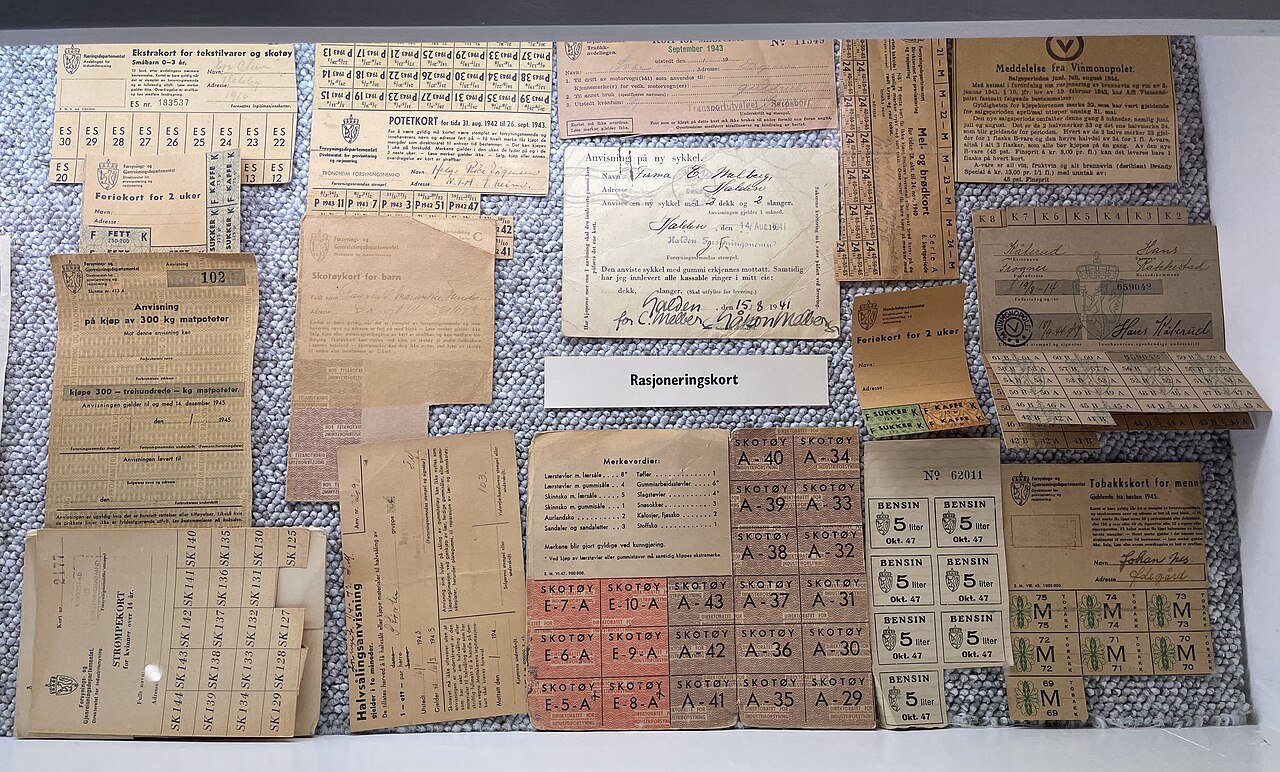A museum display of worn World War II-era ration cards and stamps for sugar, shoes, textiles, and other goods