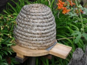 Photo of a traditional wooden bee skep, stand, and landing board at an open-air museum