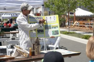 A beekeeper leading a hands-on basic beekeeping workshop, the kind of instruction typical in an apiary volunteer placement