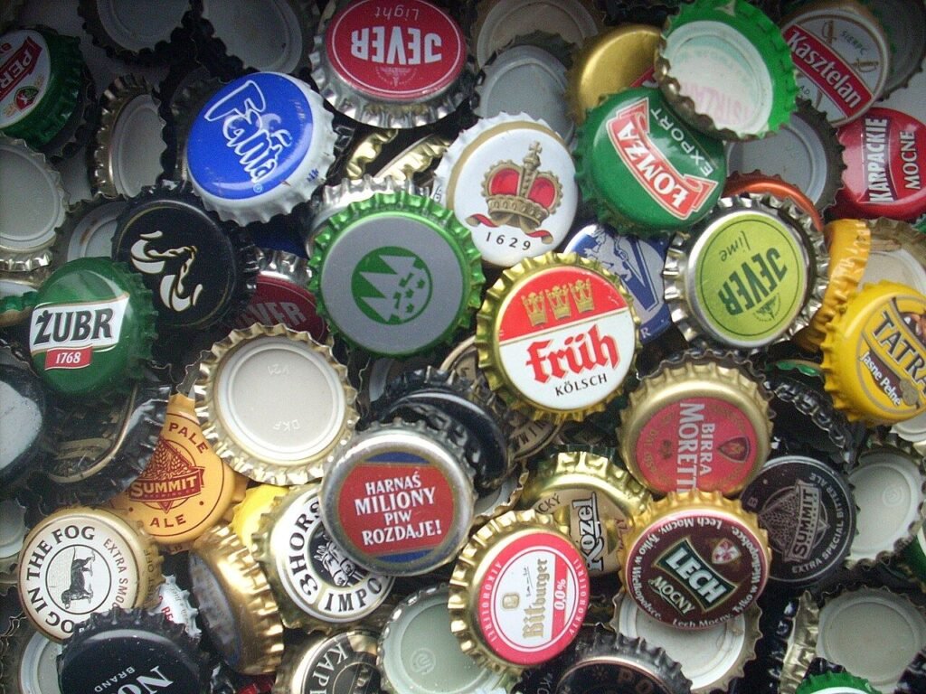 Several metal crown bottle caps, the kind of sealed closure that can turn a batch bottled too early into a dangerous pressurized bottle bomb