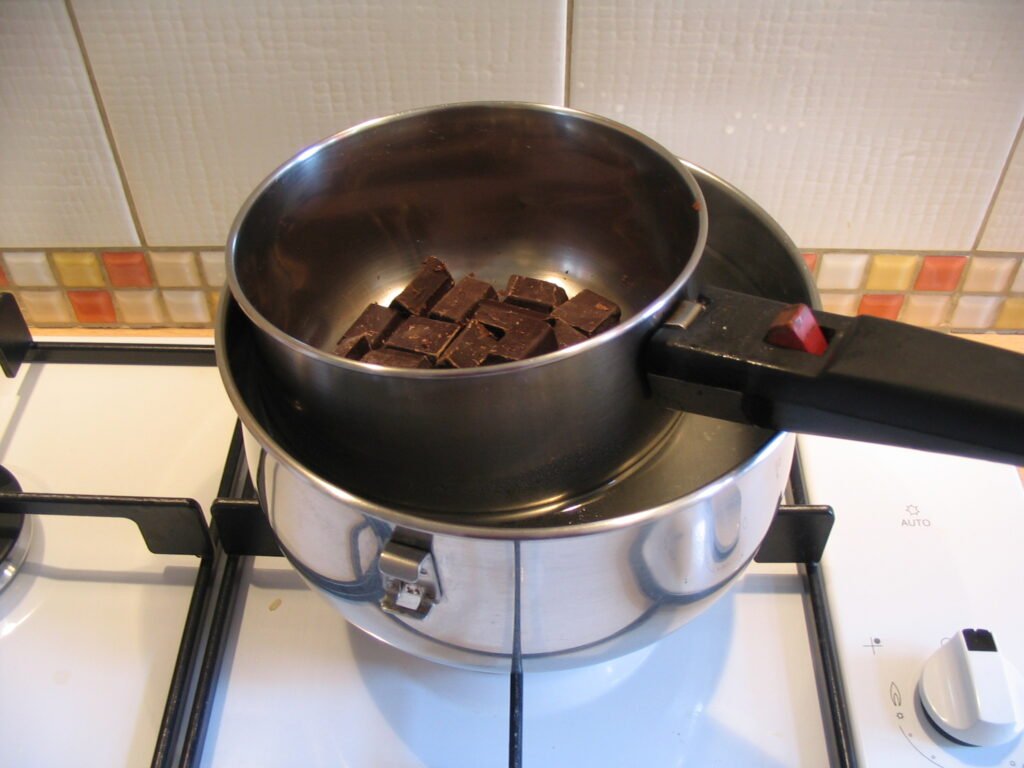 Double-boiler setup with a small pot nested over simmering water, the gentle-heat melting method