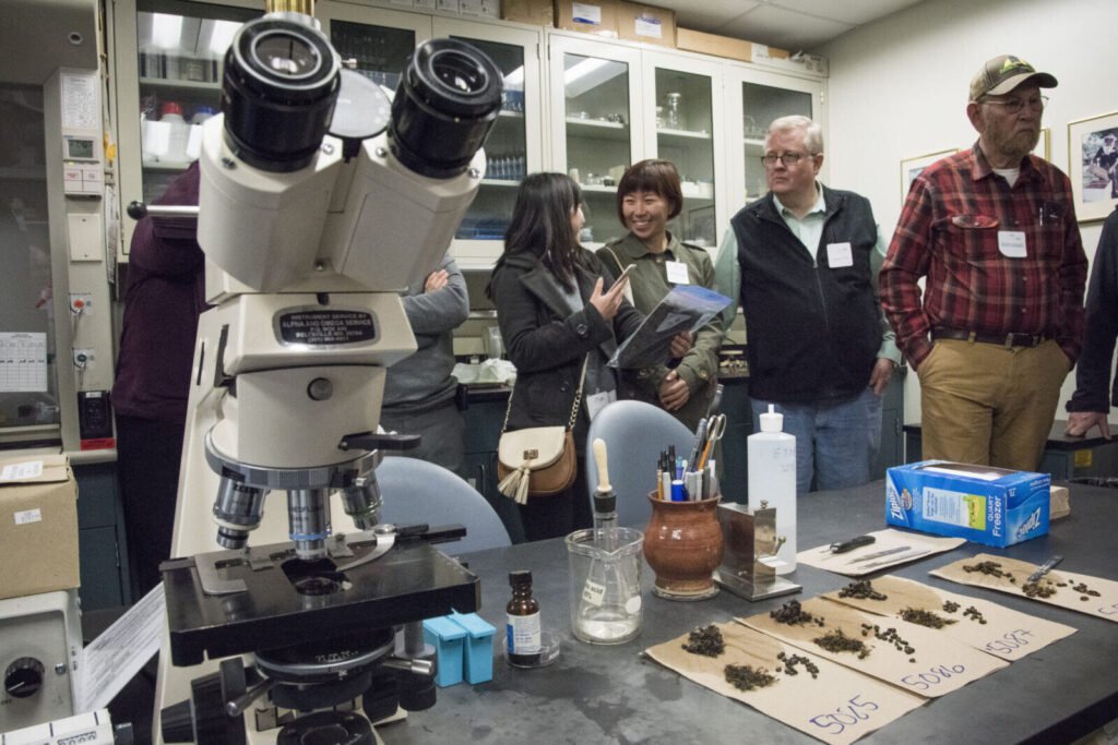 Group of visitors on an educational field trip examining a bee comb sample at an agricultural research facility
