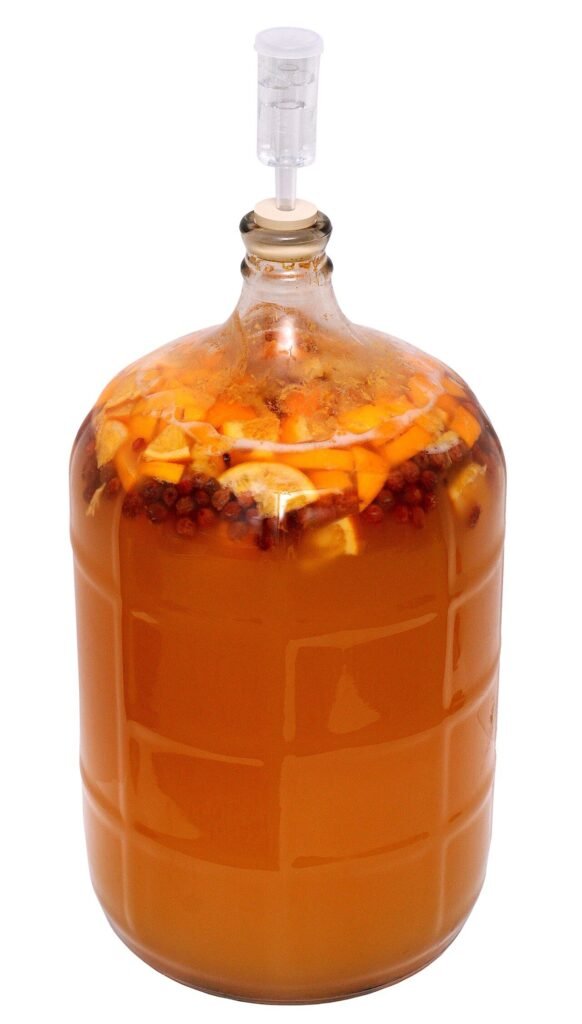 A jar of homemade honey and fruit mead actively fermenting at home