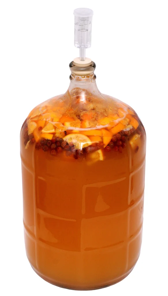 A jar of homemade honey and fruit mead actively fermenting at home