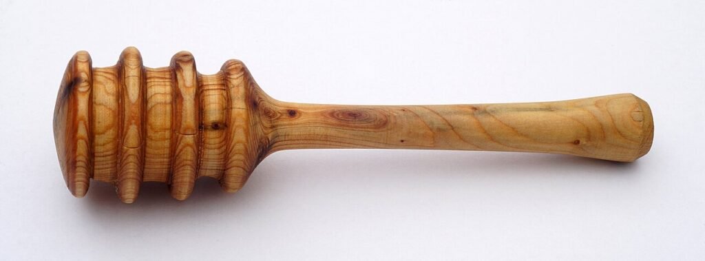 A wooden honey dipper drizzling honey, illustrating how honey choice varies by use case