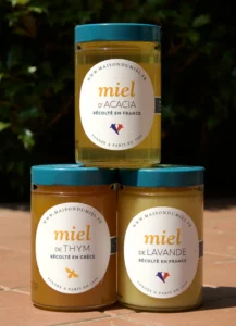 Three jars of different French monofloral honey varieties stacked side by side