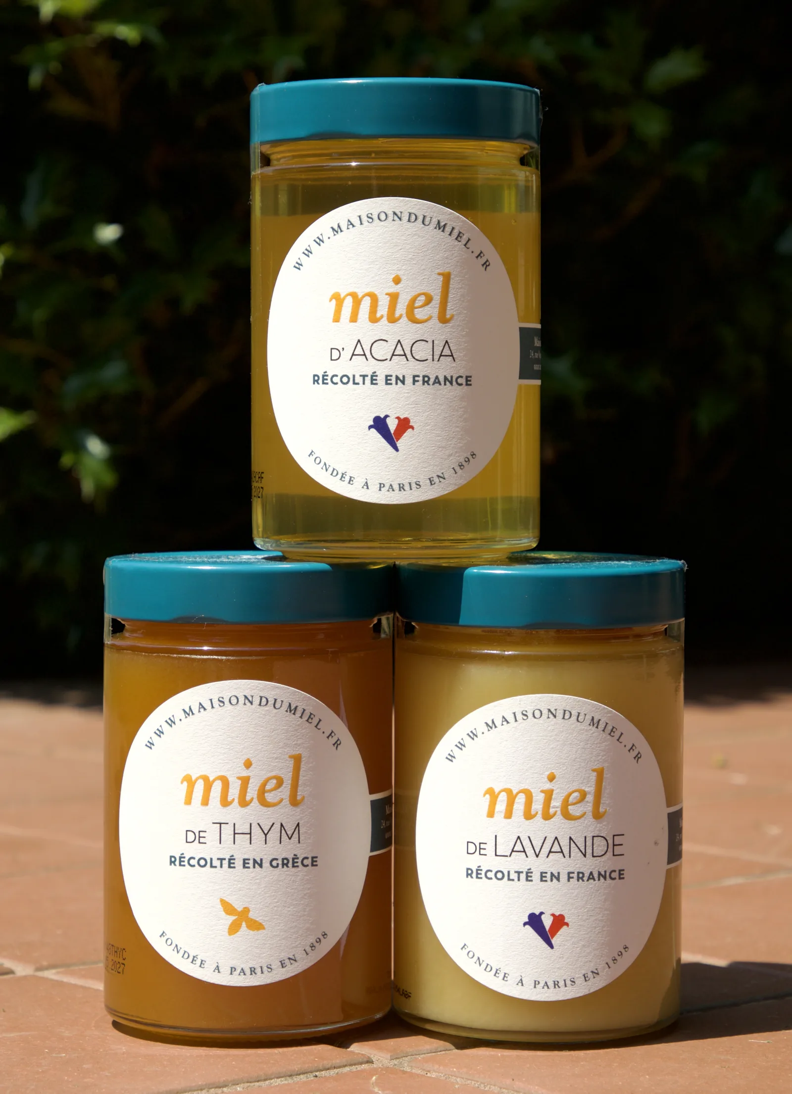 Three jars of different French monofloral honey varieties stacked side by side