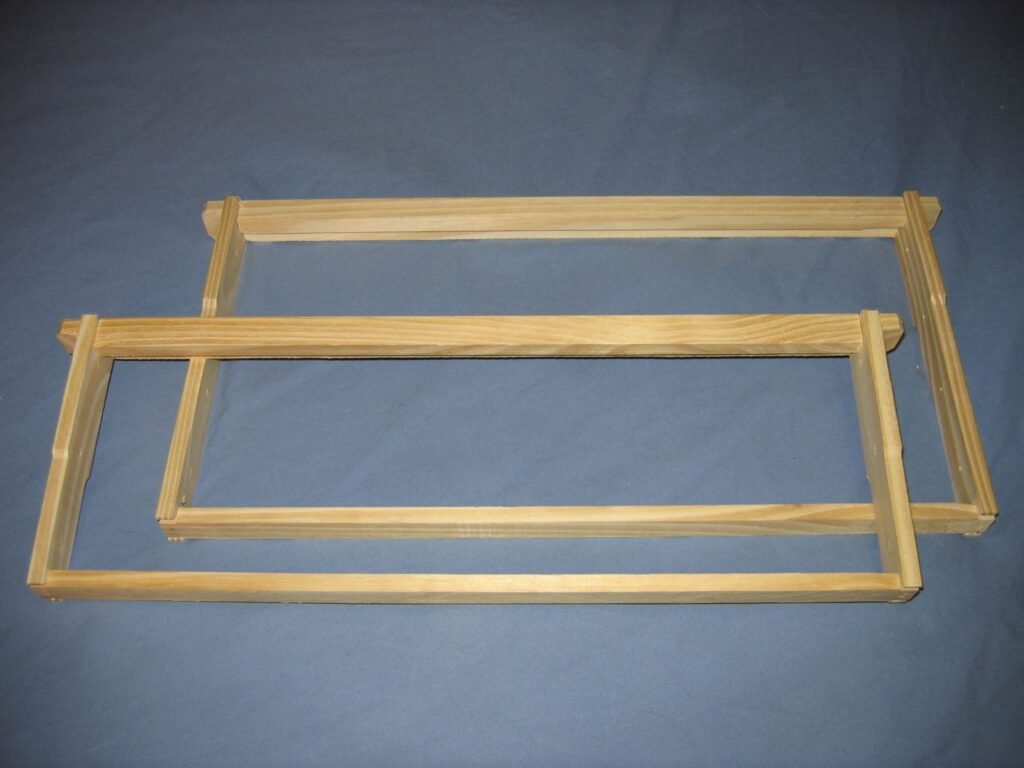 Two empty wooden Langstroth frames showing the top-bar ears, end bars and bottom bars