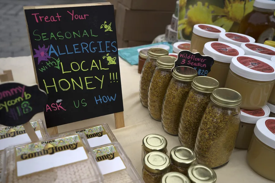 Jars of honey, bee pollen and boxed comb honey for sale on a table at the Union Square Greenmarket in Manhattan