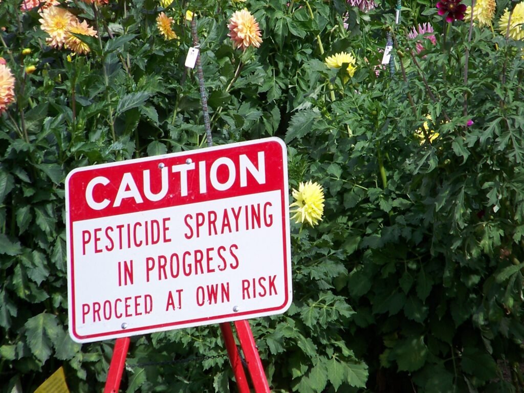 Posted caution sign warning of pesticide spraying, an example of physical notification that a digital registry supplements