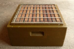 Wire mesh queen excluder placed on top of a hive box, the type of barrier used to contain Warwick Kerr's imported African queens before their 1957 escape