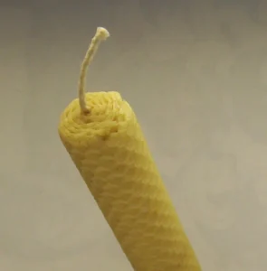 A hand-rolled pure beeswax candle showing the raw texture of rendered beeswax, the same wax base used for homemade beeswax fire starters