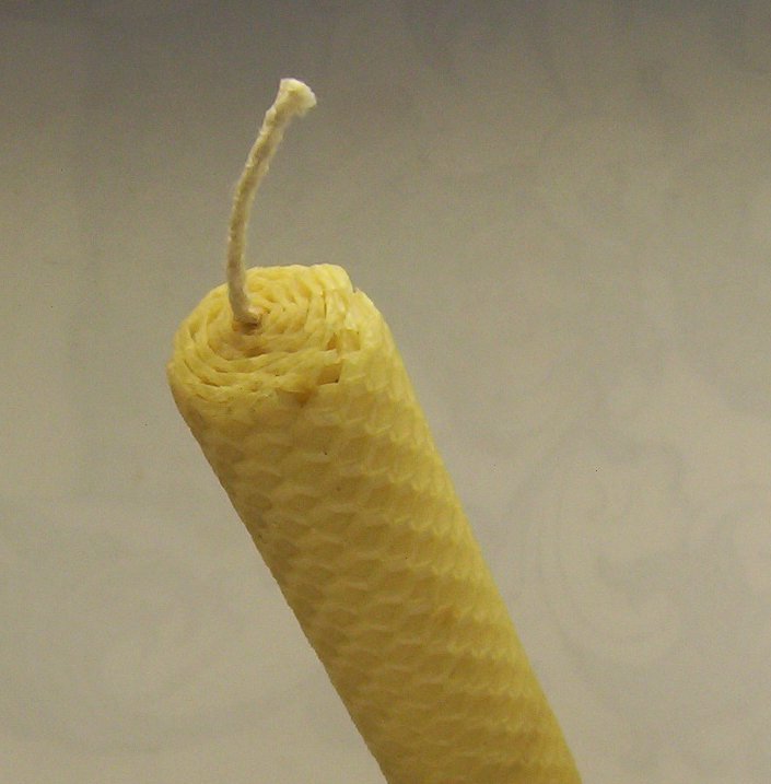 A hand-rolled pure beeswax candle showing the raw texture of rendered beeswax, the same wax base used for homemade beeswax fire starters