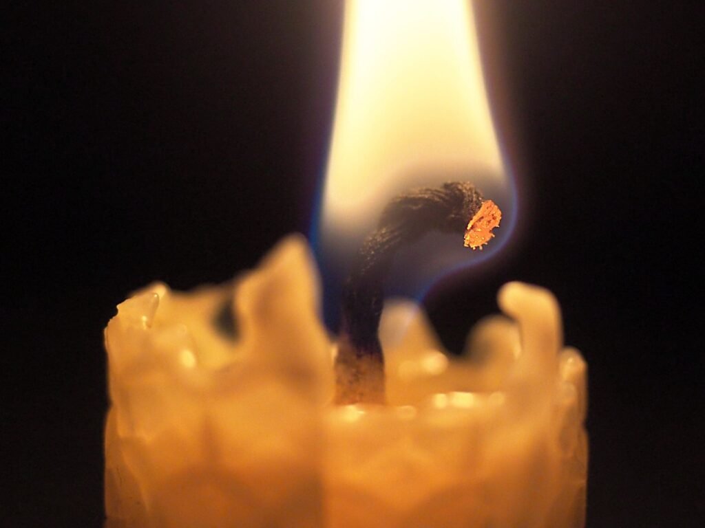 Close-up of a beeswax candle burning with a visible glowing wick