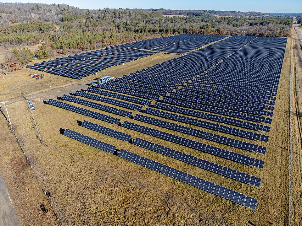Aerial view of rows of solar panels installed across a grass field, the kind of site increasingly managed as pollinator habitat under agrivoltaics programs