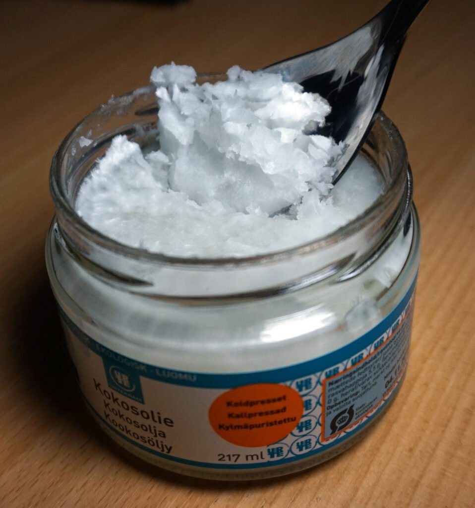 Jar of solid white coconut oil at cool room temperature, the base oil in beeswax deodorant