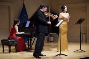 Violist performing on a Stradivari instrument on stage with pianist and singer
