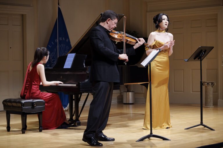 Violist performing on a Stradivari instrument on stage with pianist and singer