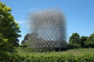 The Hive, a tall lattice aluminum sculpture at Kew Gardens surrounded by trees and meadow