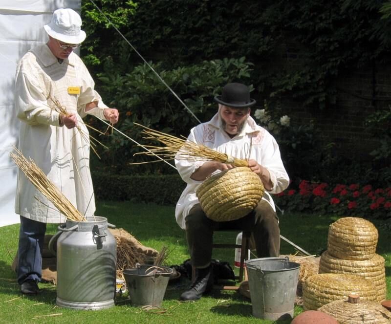 Traditional straw skep beehive being hand-woven, the type of hive draped in mourning cloth