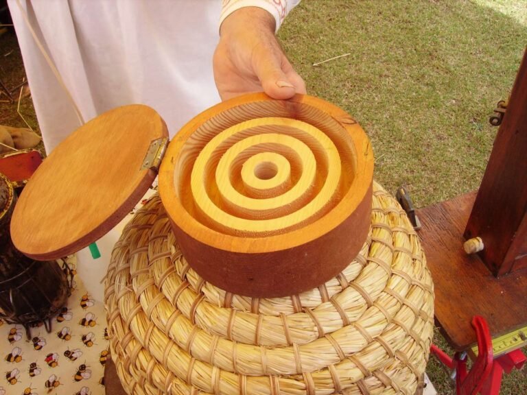 Beekeeper demonstrating a wooden hive-top feeder placed on top of a traditional straw skep hive