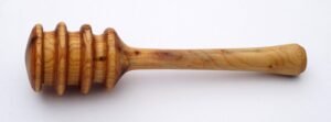 A traditional wooden honey dipper with a grooved spiral design, the classic style used to drizzle honey by surface tension