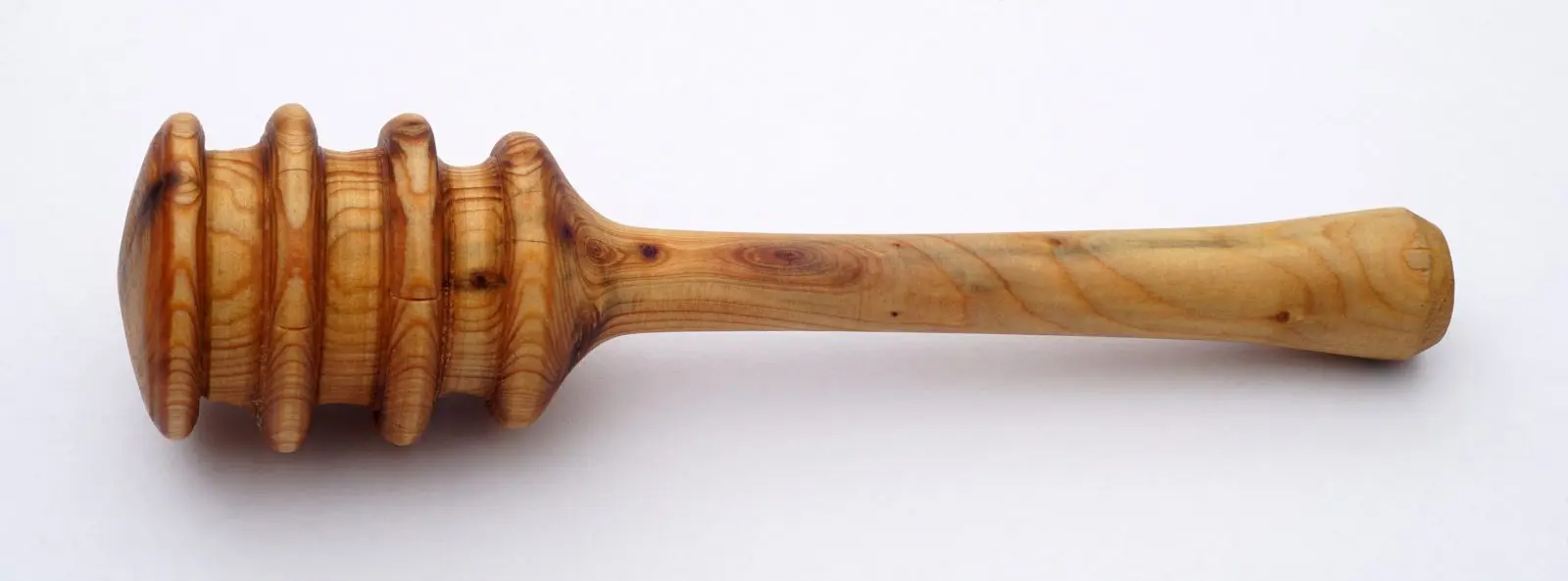 A traditional wooden honey dipper with a grooved spiral design, the classic style used to drizzle honey by surface tension