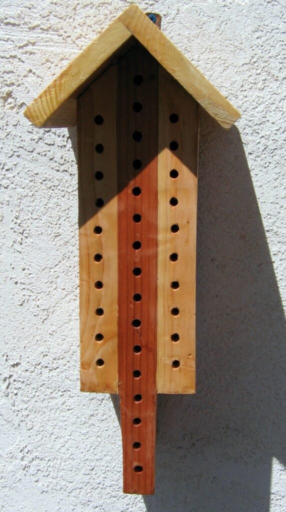 A wooden solitary bee house with drilled nesting holes, the same cavity-nesting principle behind a bee brick