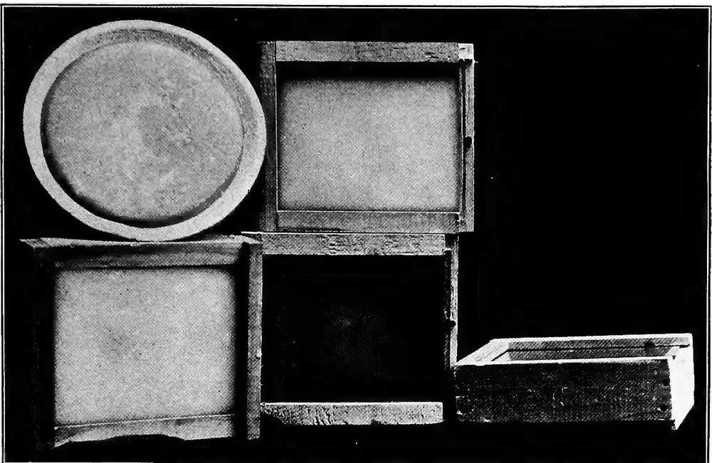 1914 photo of wooden candy feeder boxes and a pie plate of soft fondant made for feeding honey bees